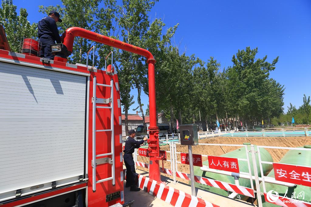  圖為：消防官兵正在通過消防水鶴為消防車加水。